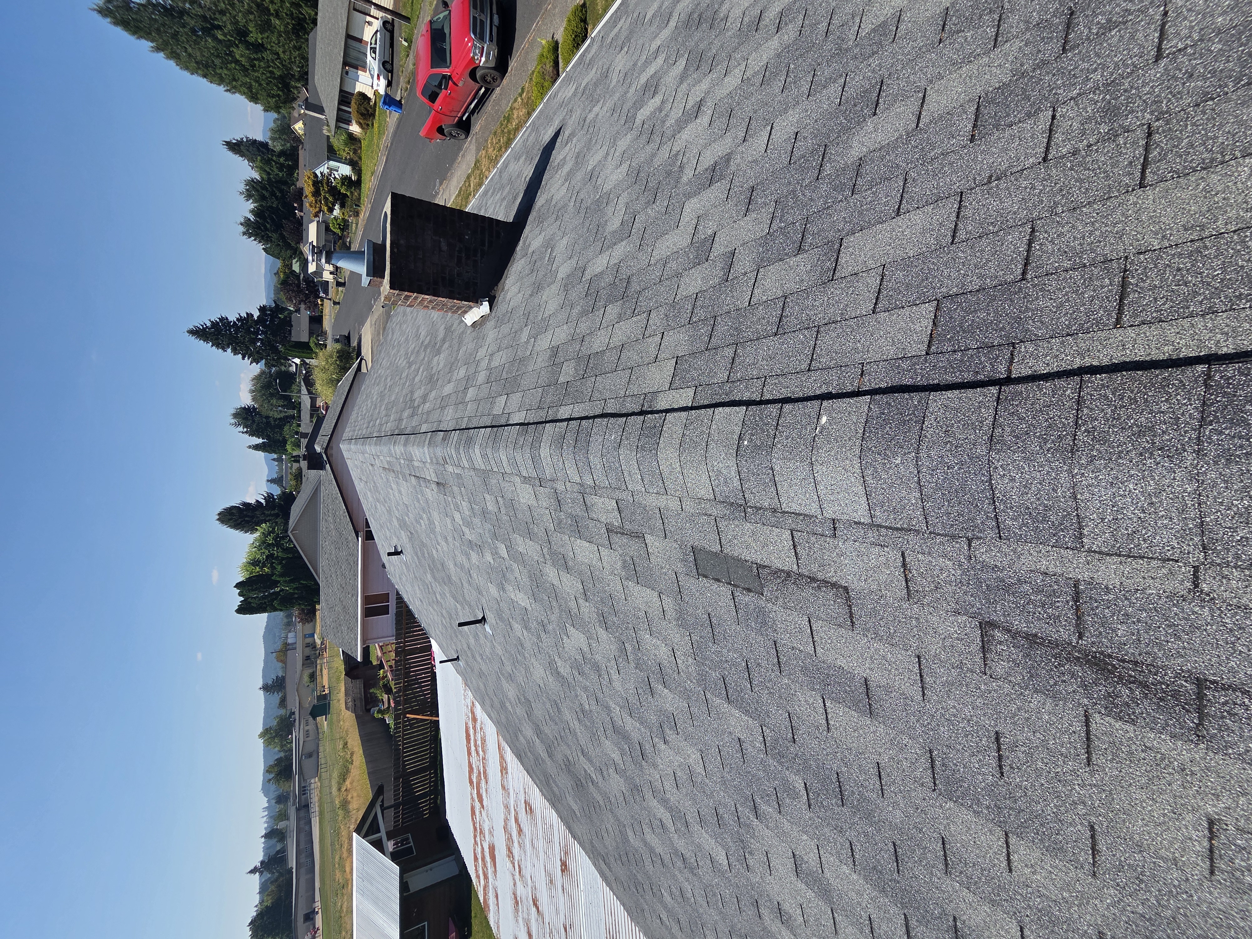 Aged and stained asphalt shingles along a roof ridge before replacement