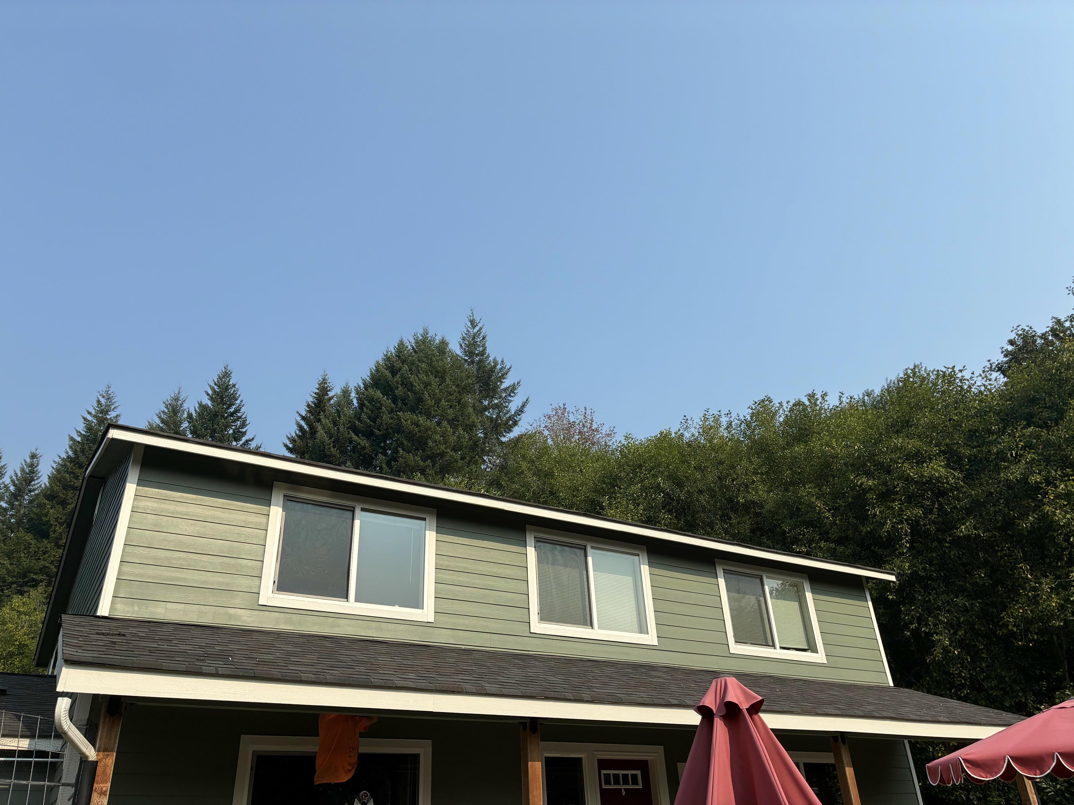 Sage green lap siding and white trim after a siding and soffit refresh