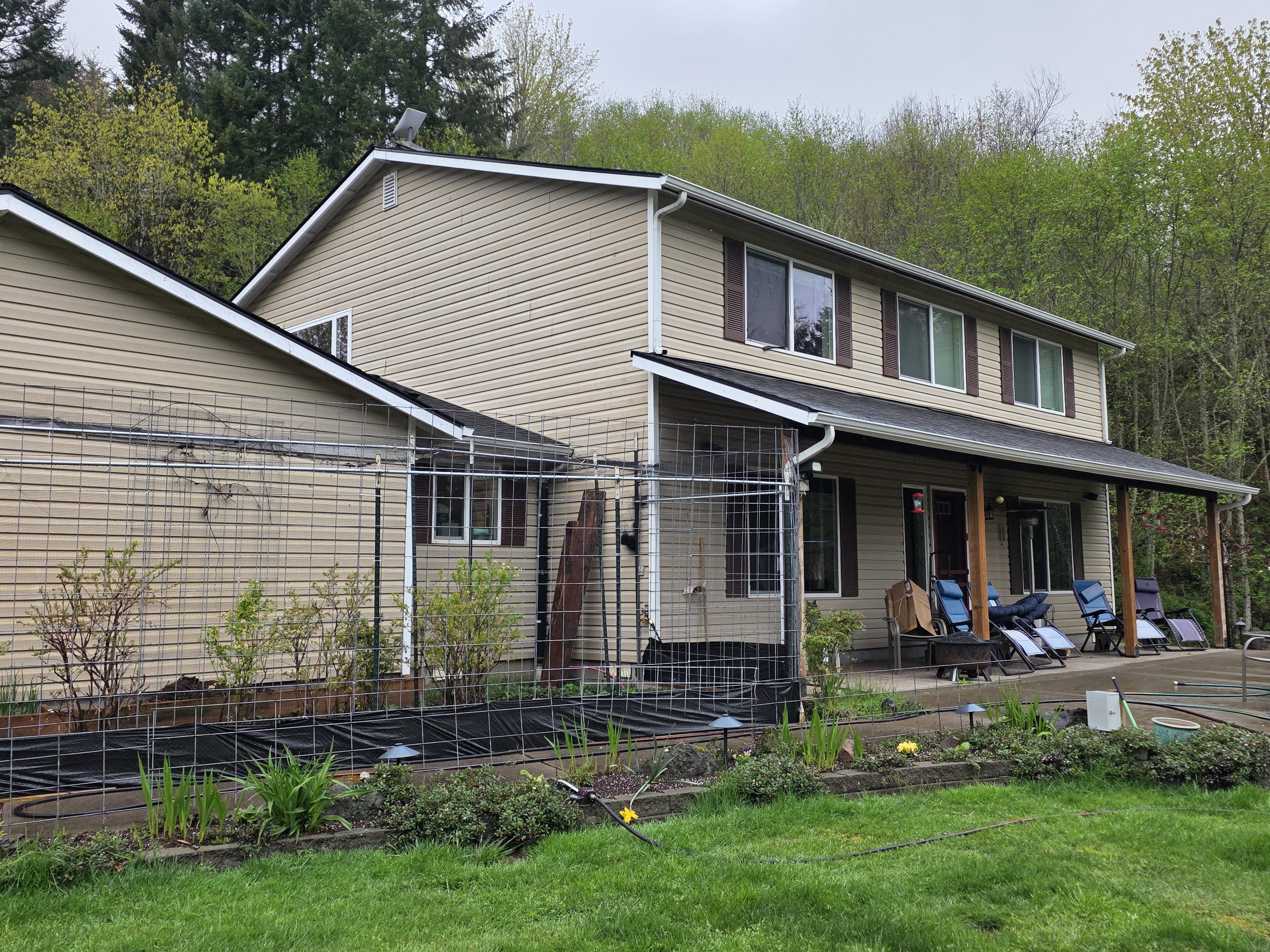 Tan lap siding and dark shutters before the siding and soffit refresh