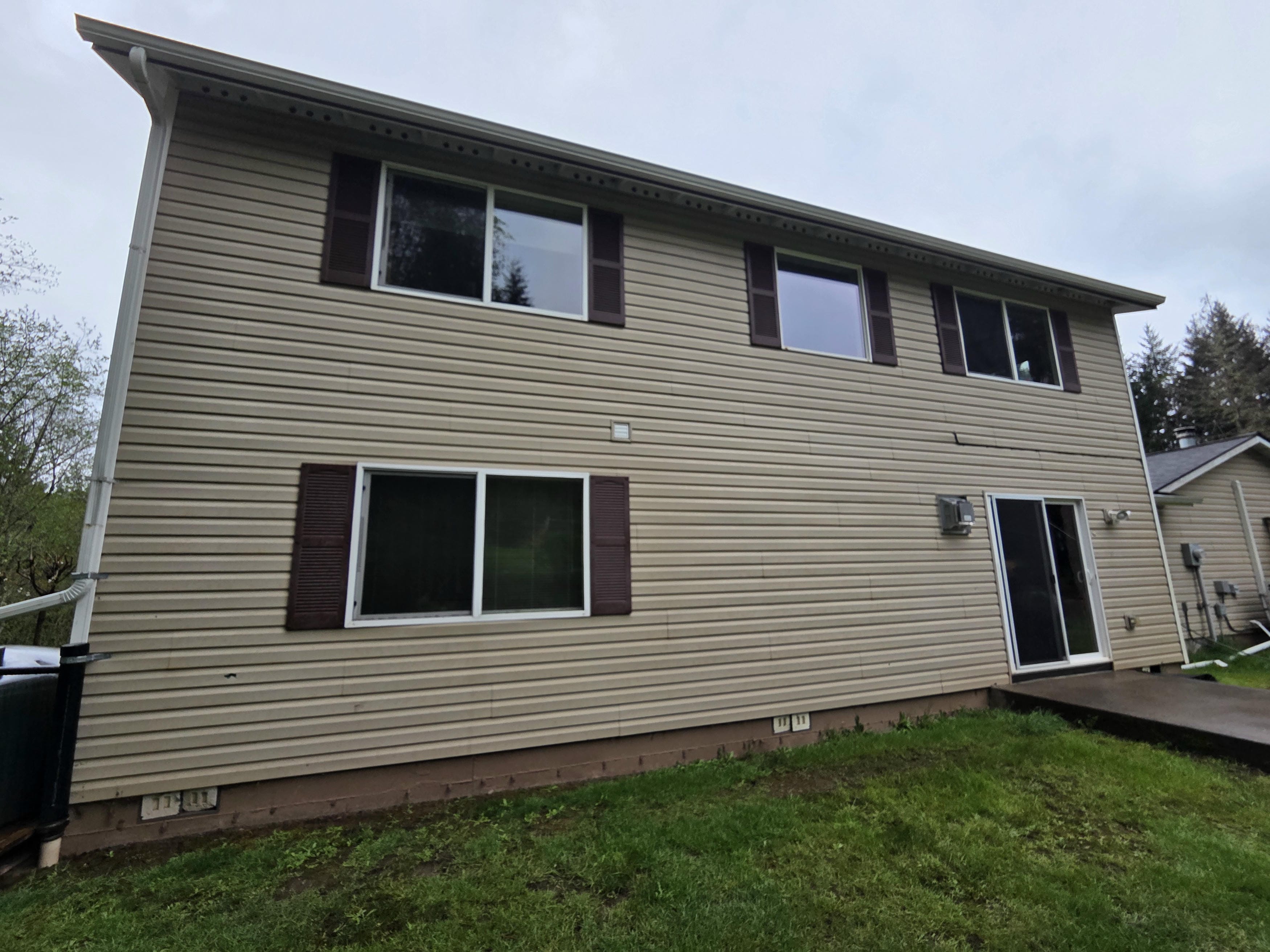 Tan lap siding and dark shutters on a two-story home before the exterior refresh