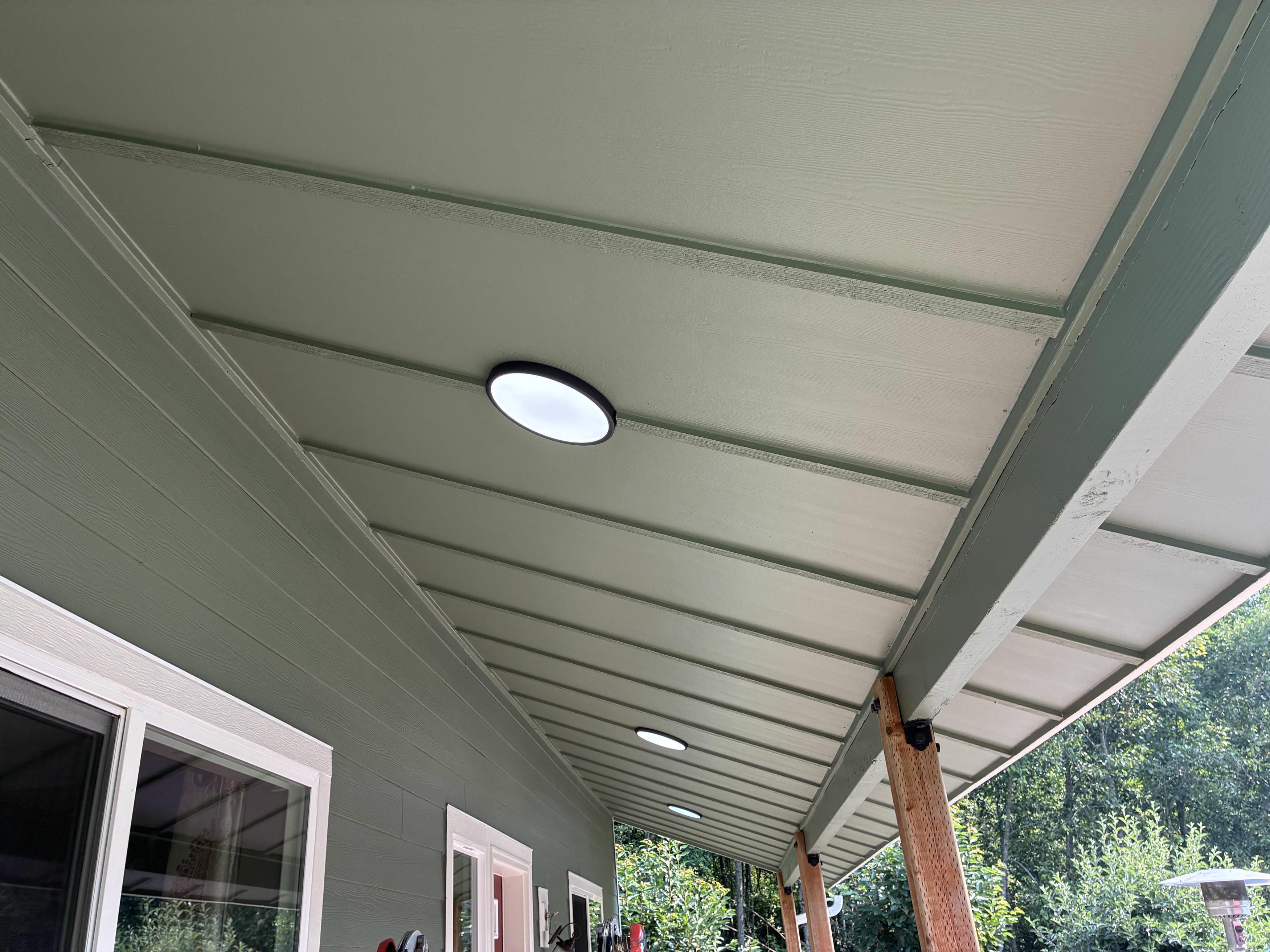 Finished sage green porch soffit with white-trimmed windows and new flush-mount lights